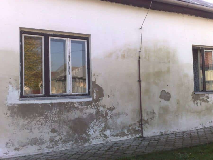 Vlhké steny domu s plesňami a poškodením spôsobeným vlhkosťou.