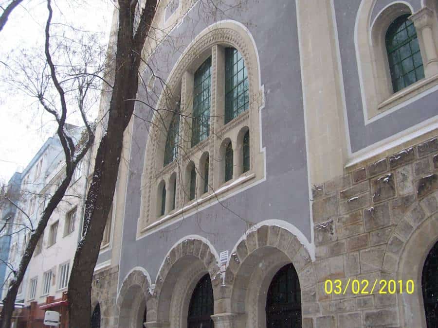 Historická budova s architektonickými oknami a archami, detail na fasáde.