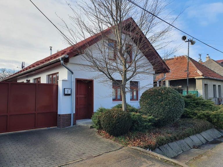 Rodinný dom s červenou strechou a záhradou, ideálny na bývanie.