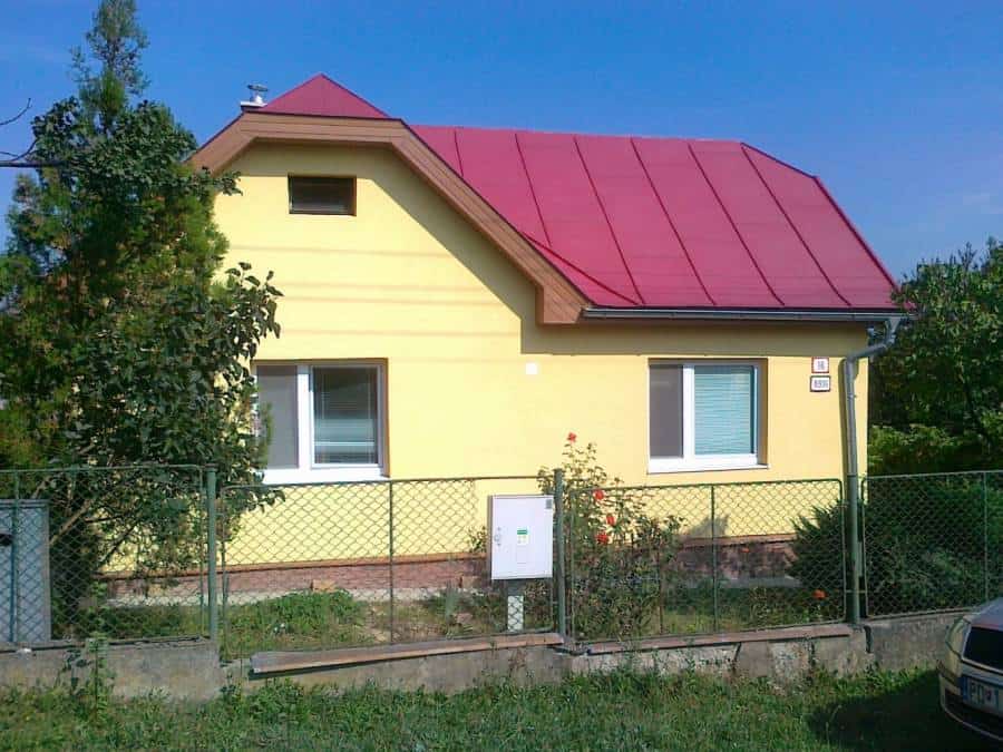 Dom s žltou fasádou a červenou strechou, ideálny na riešenie vlhkosti a izolácie s technológiou Aqua.