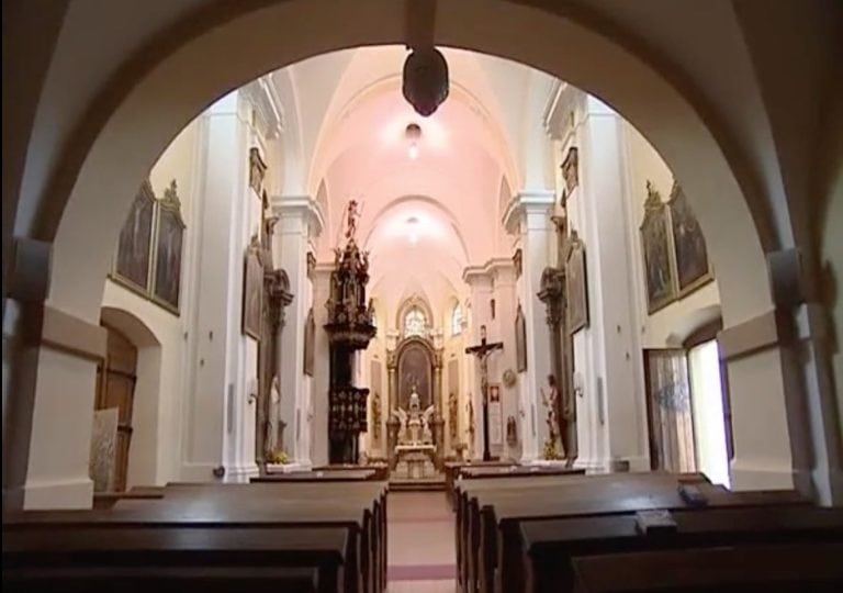 Interiér kostola s oltárom a umeleckými dielami, pokojná atmosféra.