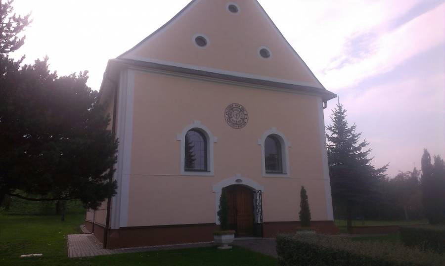 Kostol s bielou fasádou a historickými oknami na pokojnom mieste.