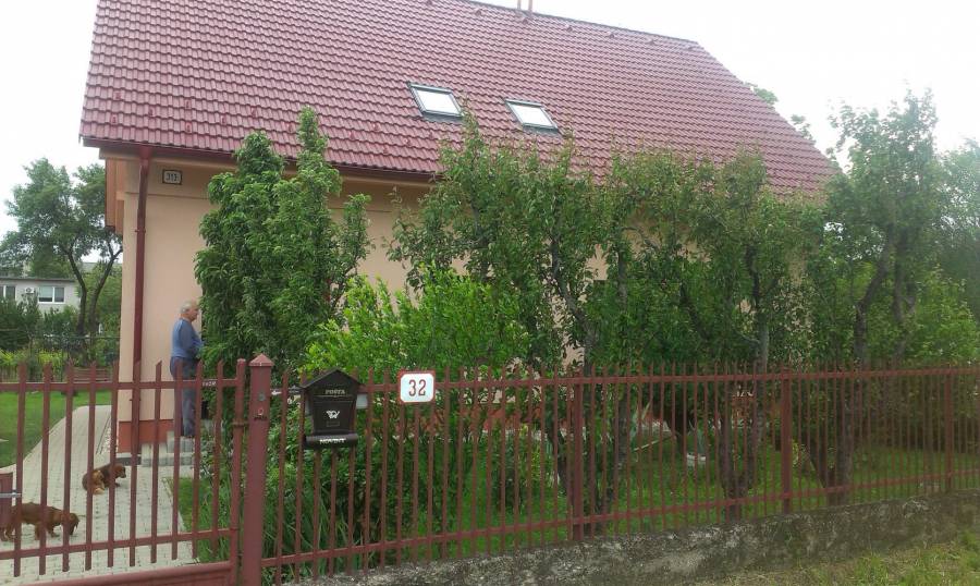Záhradný dom s ovocnými stromami a plotom, ideálne pre relaxáciu.