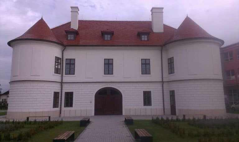Impozantná historická budova s červenou strechou a bielymi stenami, ideálna pre architektonické foto.