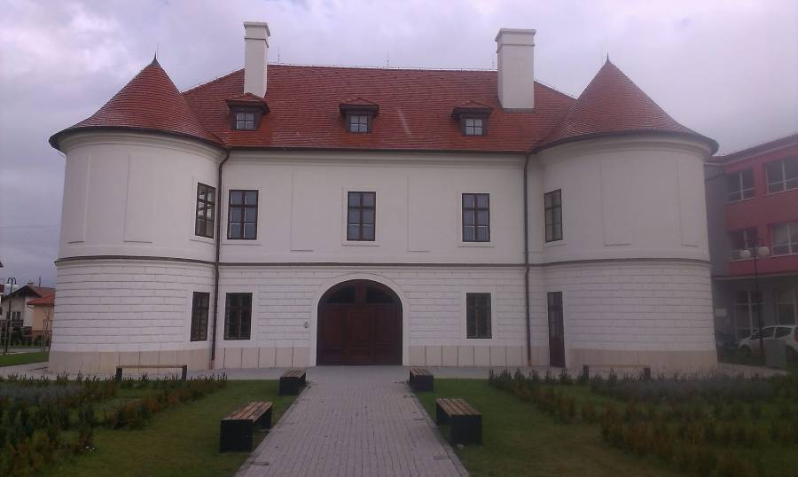 Historická budova s červenou strechou, vhodná na rekonštrukciu a obnovu.