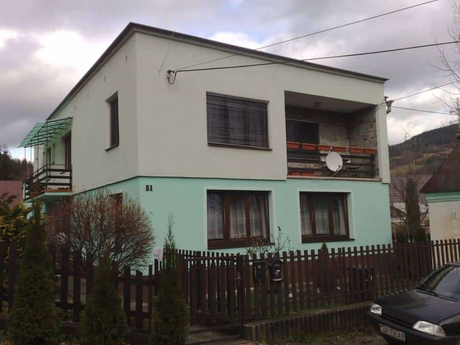 Moderná dvojposchodová rodinná vila s Aquapol systémom, zeleno-biela fasáda, obklopená dreveným plot.