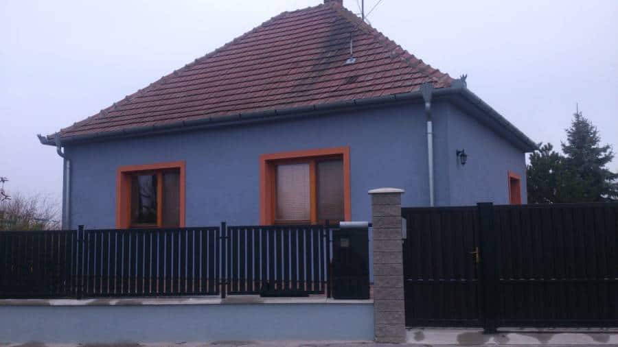 Rodinný dom s červenou strechou a moderným plotom na predmestí.