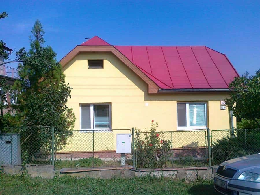 Dom s červenou strechou a žltou fasádou, ideálny pre riešenie vlhkosti a vodného zateplenia s techno.