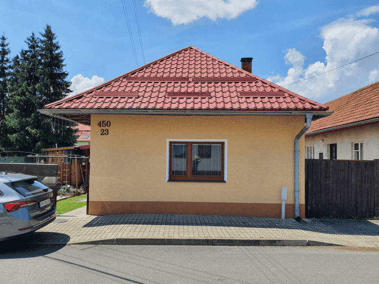 Dom s červenou strechou a číslami 450/23, ideálny pre riešenie vlhkosti a vodného zateplenia.