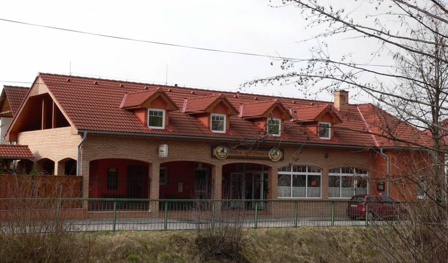 Červená strecha a moderná budova s terasou, ideálna pre komerčné využitie alebo bývanie.